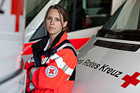 Frau in Dienstkleidung vor einem Rettungswagen