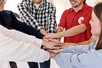 Symbolfoto Mitarbeitende vom DRK legen ihre Hände übereinander