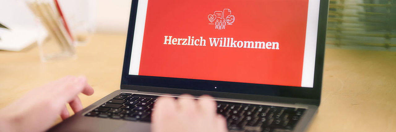 Symbolfoto, das Wort ‚Willkommen‘ und DRK - Logo auf dem Bildschirm eines Laptops