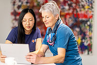 Zwei Damen über einen Laptop gebeugt