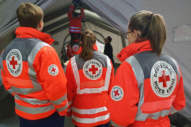 Team in Einsatzjacken schaut in ein Zelt