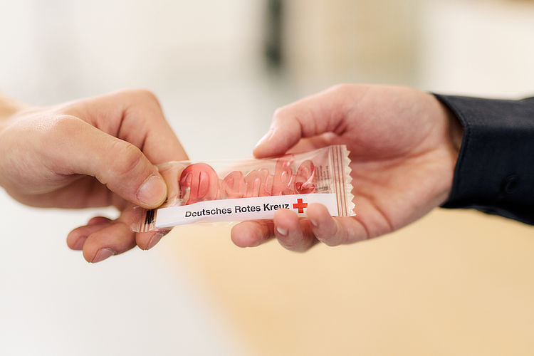 Symbolfoto, Give away des DRK, roter Weingummi in Form des Schriftzuges ‚Danke‘, in der Verpackung