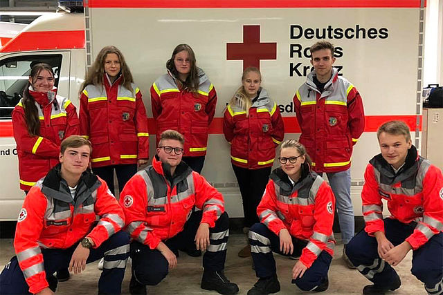 JRK Team in Dienstbekleidung vor einem Rettungswagen