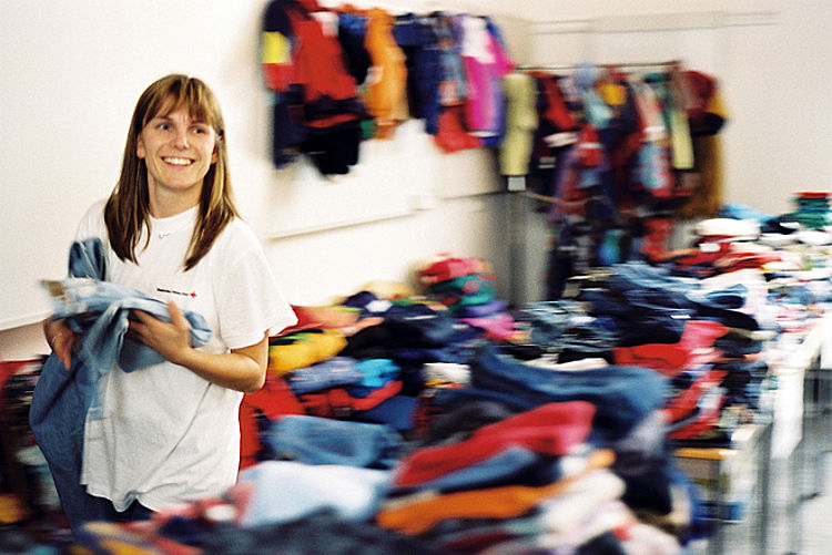 Frau sucht sich eine Jeans in der Kleiderkammer aus