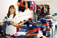Frau sucht sich eine Jeans in der Kleiderkammer aus