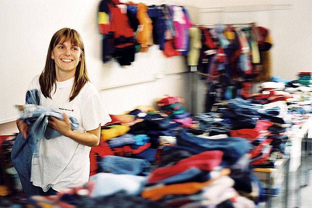Frau sucht sich eine Jeans in der Kleiderkammer aus