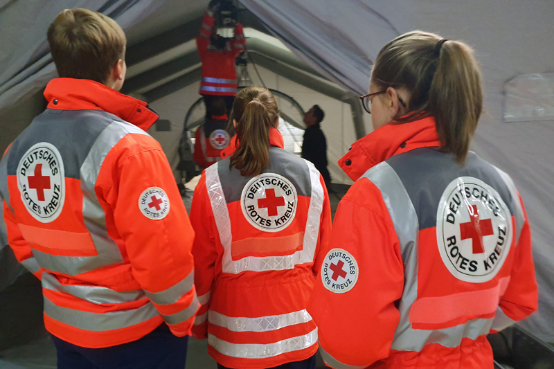 Team in Einsatzjacken schaut in ein Zelt